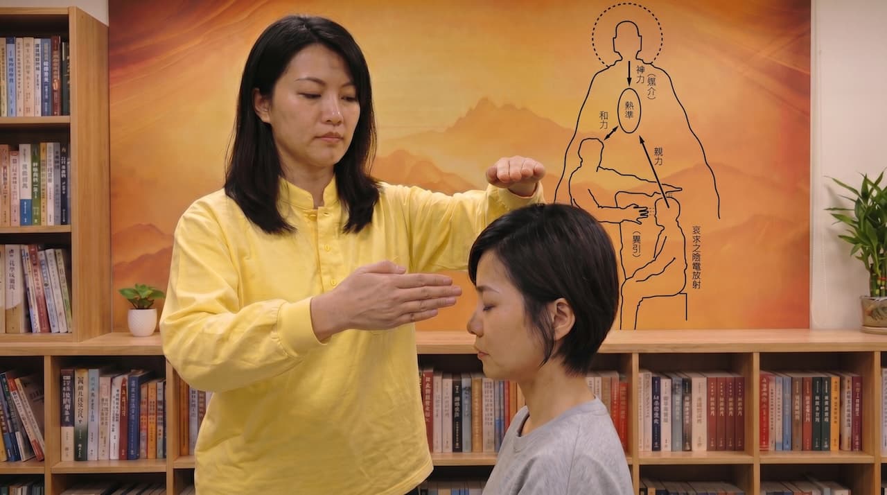 同奮（穿黃色上衣）站立，雙手輕舉，為安靜坐著的受調者進行天人炁功服務。背景牆上懸掛精神治療原理圖，標示神力、熱準、親力、和力等概念。