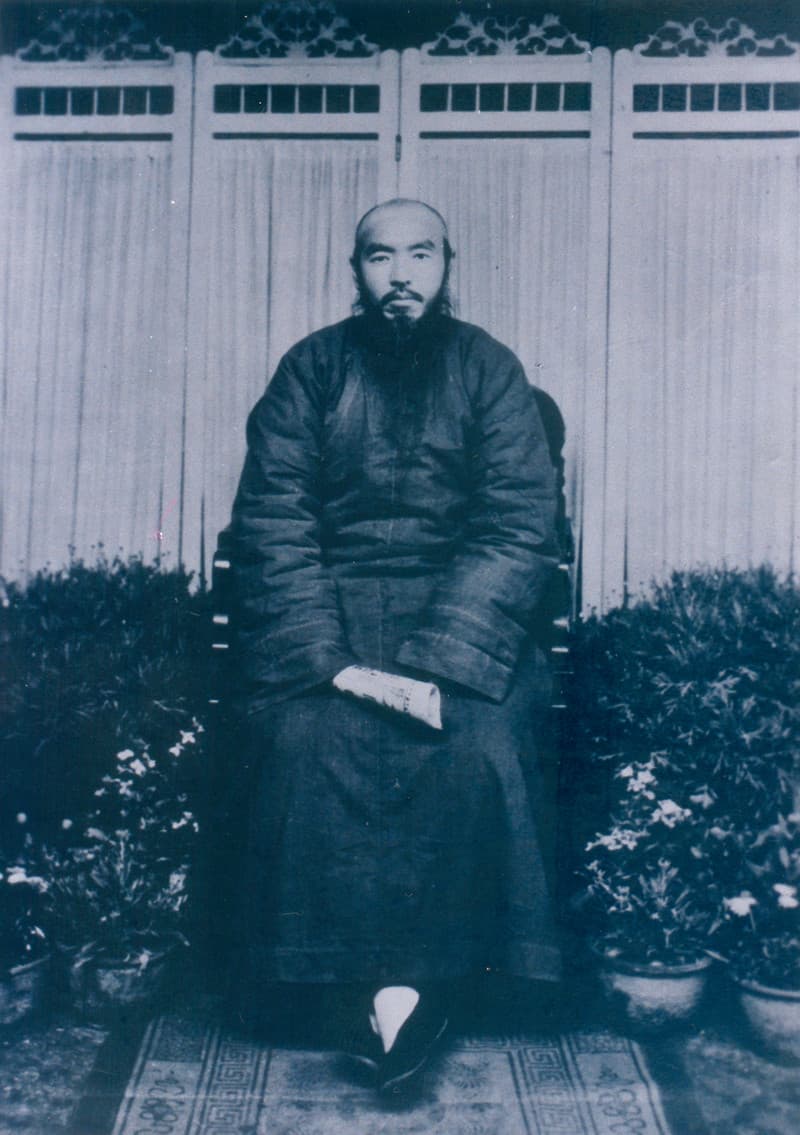 天德教教主蕭公昌明的正式肖像照，約攝於民國初年。蓄鬚的他身著深色長袍，端坐椅上，手持一卷文書，背景為格扇屏風與盆花，神態端莊威嚴。