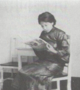 坤元輔教青年時期照片，畫面中坤元輔教坐在椅子上閱讀書報雜誌